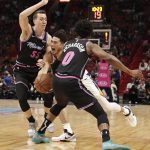 Phoenix Suns guard Devin Booker, center, pushes through Miami Heat forward Duncan Robinson (55) and guard Josh Richardson (0) during the first half of an NBA basketball game Monday, Feb. 25, 2019, in Miami. (AP Photo/Brynn Anderson)