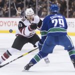 Arizona Coyotes' Vinnie Hinostroza (13) flips the puck past Vancouver Canucks' Ashton Sautner during the first period of an NHL hockey game Thursday, Feb. 21, 2019, in Vancouver, British Columbia. (Darryl Dyck/The Canadian Press via AP)