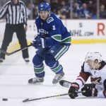 Arizona Coyotes' Josh Archibald, front right, falls while reaching for the puck in front of Vancouver Canucks' Derrick Pouliot during the first period of an NHL hockey game Thursday, Feb. 21, 2019, in Vancouver, British Columbia. (Darryl Dyck/The Canadian Press via AP)