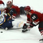 Arizona Coyotes right wing Conor Garland (83) tries to clear the puck as St. Louis Blues center Oskar Sundqvist (70) sits on the ice near Coyotes goaltender Darcy Kuemper, back, during the third period of an NHL hockey game Thursday, Feb. 14, 2019, in Glendale, Ariz. The Blues won 4-0. (AP Photo/Ross D. Franklin)