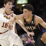 Phoenix Suns' Devin Booker (1) drives past Cleveland Cavaliers' Cedi Osman (16), from Turkey, in the second half of an NBA basketball game, Thursday, Feb. 21, 2019, in Cleveland. (AP Photo/Tony Dejak)