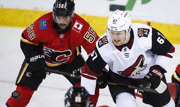 Arizona Coyotes' Lawson Crouse, right, and Calgary Flames' Oliver Kylington, of Sweden, scramble fo...