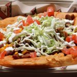 505 Fry Bread Taco: Native fry bread with ranch beans, carnitas, green chile sauce, cheddar cheese, lettuce, tomato, sour cream — $14