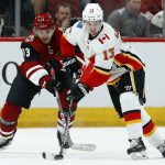 Calgary Flames left wing Johnny Gaudreau, right, tries to keep the puck away from Arizona Coyotes center Vinnie Hinostroza, left, during the first period of an NHL hockey game Thursday, March 7, 2019, in Glendale, Ariz. (AP Photo/Ross D. Franklin)