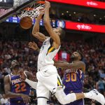 Utah Jazz center Rudy Gobert, center, dunks on Phoenix Suns' Deandre Ayton (22) and Troy Daniels (30) during the second half of an NBA basketball game Monday, March 25, 2019, in Salt Lake City. (AP Photo/Rick Bowmer)