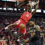 Houston Rockets' Kenneth Faried (35) hangs on the rim after dunking the ball as Phoenix Suns' Troy Daniels (30) avoids him during the second half of an NBA basketball game Friday, March 15, 2019, in Houston. The Rockets won 108-102. (AP Photo/David J. Phillip)