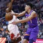 Phoenix Suns guard Devin Booker (1) passes around Chicago Bulls guard Antonio Blakeney during the first half of an NBA basketball game, Monday, March 18, 2019, in Phoenix. (AP Photo/Matt York)