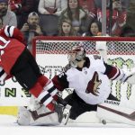 New Jersey Devils center Blake Coleman (20) trips over Arizona Coyotes goaltender Darcy Kuemper (35) while scoring during a shootout in an NHL hockey game, Saturday, March 23, 2019, in Newark, N.J. The Devils on 2-1 in a shootout. (AP Photo/Julio Cortez)