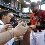 A fan with a baseball stitch tattoo reaches for an autograph from Arizona Diamondbacks' Steven Souza Jr. before a spring training baseball game against the Chicago White Sox, Monday, March 25, 2019, in Phoenix, Ariz. (AP Photo/Elaine Thompson)