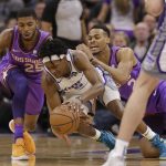 Sacramento Kings guard De'Aaron Fox, center, dives for the ball between Phoenix Suns' Mikal Bridges, left, and Elie Okobo during the first quarter of an NBA basketball game Saturday, March 23, 2019, in Sacramento, Calif. (AP Photo/Rich Pedroncelli)