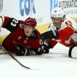 Arizona Coyotes defenseman Oliver Ekman-Larsson (23) tries to pass the puck as he goes down to the ice with Calgary Flames left wing Matthew Tkachuk (19) during the first period of an NHL hockey game Thursday, March 7, 2019, in Glendale, Ariz. (AP Photo/Ross D. Franklin)