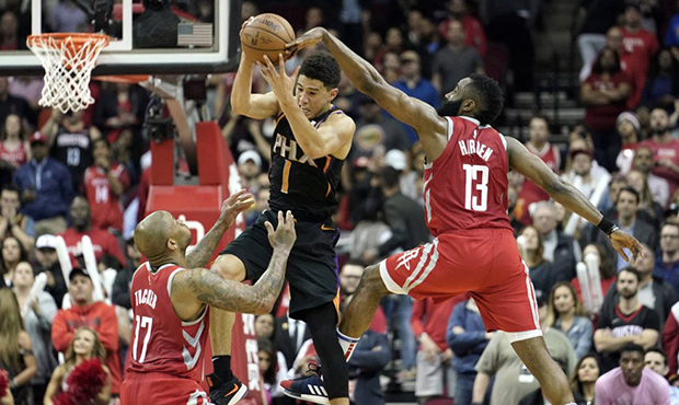 Phoenix Suns' Devin Booker (1) leaps to catch a pass as Houston Rockets' James Harden (13) and PJ T...