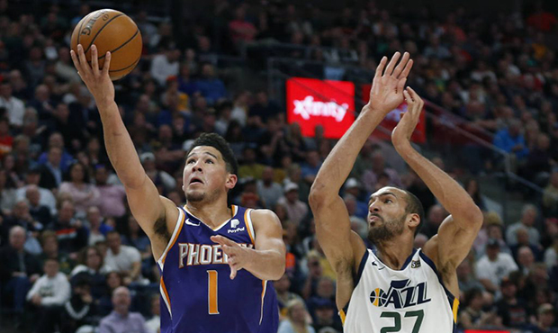 Phoenix Suns guard Devin Booker (1) lays up the ball as Utah Jazz center Rudy Gobert (27) defends d...