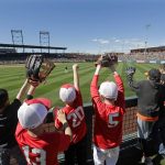 Children line the left field fence as they call for a ball from players warming up between innings of a spring training baseball game between the San Francisco Giants and the Arizona Diamondbacks, Thursday, March 14, 2019, in Scottsdale, Ariz. (AP Photo/Elaine Thompson)