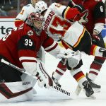 Calgary Flames left wing Johnny Gaudreau (13) collides with Arizona Coyotes goaltender Darcy Kuemper (35) during the first period of an NHL hockey game Thursday, March 7, 2019, in Glendale, Ariz. (AP Photo/Ross D. Franklin)