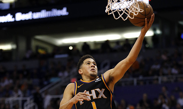 Phoenix Suns guard Devin Booker (1) drives past Memphis Grizzlies forward Justin Holiday (7) and De...