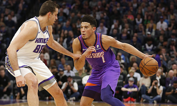 Phoenix Suns guard Devin Booker, right, drives against Sacramento Kings forward Nemanja Bjelica dur...