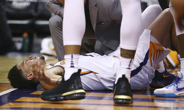 An injured Phoenix Suns guard Devin Booker pauses on the floor after turning his ankle during the f...