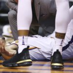 An injured Phoenix Suns guard Devin Booker pauses on the floor after turning his ankle during the first half of the team's NBA basketball against the Utah Jazz Wednesday, April 3, 2019, in Phoenix. Booker left the game. (AP Photo/Ross D. Franklin)