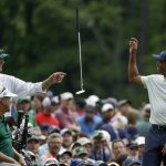 Tiger Woods smiles as caddie Joe LaCava tosses his putter on the 12th hole during the second round for the Masters golf tournament Friday, April 12, 2019, in Augusta, Ga. (AP Photo/Chris Carlson)