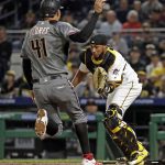 Pittsburgh Pirates catcher Elias Diaz, right, takes the toss from relief pitcher Kyle Crick as Arizona Diamondbacks' Wilmer Flores (41) scores from third on an infield hit by Blake Swihart during the seventh inning of a baseball game in Pittsburgh, Monday, April 22, 2019. (AP Photo/Gene J. Puskar)