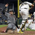 Pittsburgh Pirates relief pitcher Kyle Crick, bottom right, tosses to catcher Elias Diaz (32) after fielding a ball hit by Arizona Diamondbacks' Blake Swihart, as Wilmer Flores (41) scores from third on the play during the seventh inning of a baseball game in Pittsburgh, Monday, April 22, 2019. (AP Photo/Gene J. Puskar)