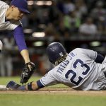 San Diego Padres shortstop Fernando Tatis Jr. dives under the tag by Arizona Diamondbacks first baseman Wilmer Flores, left, to get back to first base safely during the eighth inning of a baseball game Thursday, April 11, 2019, in Phoenix. The Padres won 7-6. (AP Photo/Ross D. Franklin)
