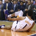 An injured Phoenix Suns guard Devin Booker reaches for his ankle after turning it during the first half of the team's NBA basketball against the Utah Jazz on Wednesday, April 3, 2019, in Phoenix. (AP Photo/Ross D. Franklin)