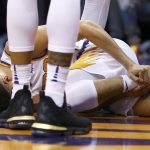 An injured Phoenix Suns guard Devin Booker holds his ankle after turning it during the first half of the team's NBA basketball against the Utah Jazz on Wednesday, April 3, 2019, in Phoenix. (AP Photo/Ross D. Franklin)