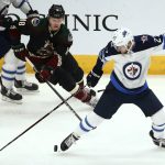 Winnipeg Jets left wing Nikolaj Ehlers (27) kicks the puck as Arizona Coyotes center Christian Dvorak (18) closes in during the second period of an NHL hockey game Saturday, April 6, 2019, in Glendale, Ariz. (AP Photo/Ross D. Franklin)