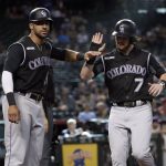 Colorado Rockies' Brendan Rodgers (7) and Ian Desmond celebrate after scoring on a base hit by Chris Iannetta during the 10th inning of the team's baseball game against the Arizona Diamondbacks, Thursday, June 20, 2019, in Phoenix. (AP Photo/Matt York)
