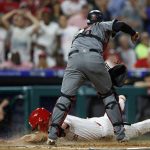 Philadelphia Phillies' Rhys Hoskins, bottom, scores past Arizona Diamondbacks catcher Carson Kelly on a RBI-double by J.T. Realmuto during the fifth inning of a baseball game, Tuesday, June 11, 2019, in Philadelphia. Philadelphia won 7-4. (AP Photo/Matt Slocum)