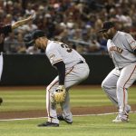 San Francisco Giants starting pitcher Tyler Beede, middle, and third baseman Pablo Sandoval, right, watch a slow grounder hit by Arizona Diamondbacks' Ildemaro Vargas roll down the third base line as Diamondbacks third base coach Tony Perezchica, left, also watches during the fourth inning of a baseball game Saturday, June 22, 2019, in Phoenix. The ball eventually rolled foul. (AP Photo/Ross D. Franklin)