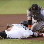 Arizona Diamondbacks' Ketel Marte, left, dives safely back into third base with a triple as San Francisco Giants shortstop Brandon Crawford, right, applies a late tag during the first inning of a baseball game Friday, June 21, 2019, in Phoenix. (AP Photo/Ross D. Franklin)