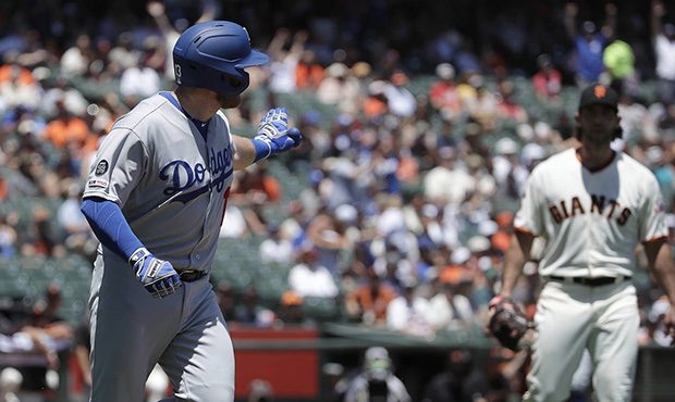 Los Angeles Dodgers' Max Muncy, left, gestures while running up the first base line after hitting a...