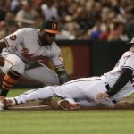Arizona Diamondbacks' Jake Lamb (22) advances safely to third on a sacrifice fly by Nick Ahmed as Baltimore Orioles' Hanser Alberto, left, makes the tag during the third inning of a baseball game, Monday, July 22, 2019, in Phoenix. (AP Photo/Matt York)