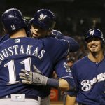 Milwaukee Brewers' Christian Yelich celebrates his two-run home run against the Arizona Diamondbacks with Mike Moustakas (11) as Brewers' Tyler Saladino (13) looks on during the seventh inning of a baseball game Friday, July 19, 2019, in Phoenix. (AP Photo/Ross D. Franklin)