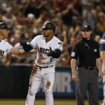 Arizona Diamondbacks' Eduardo Escobar (5) celebrates his RBI triple with third base coach Tony Perezchica, left, near umpire Sean Barber, second from right, and Milwaukee Brewers starting pitcher Jhoulys Chacin during the third inning of a baseball game Friday, July 19, 2019, in Phoenix. (AP Photo/Ross D. Franklin)