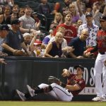 Arizona Diamondbacks left fielder Tim Locastro, front left, tosses the ball into the infield after making a diving catch on a foul ball hit by Milwaukee Brewers' Mike Moustakas as Diamondbacks third baseman Jake Lamb (22) looks on during the first inning of a baseball game Sunday, July 21, 2019, in Phoenix. (AP Photo/Ross D. Franklin)