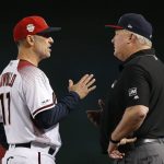 Arizona Diamondbacks manager Torey Lovullo, left, argues with umpire Bill Miller, right, after Miller called Diamondbacks' Zack Greinke for interference during the third inning of a baseball game against the Colorado Rockies, Friday, July 5, 2019, in Phoenix. (AP Photo/Ross D. Franklin)