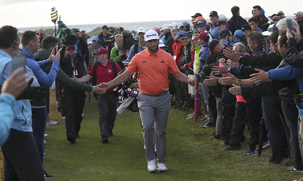 Spain's Jon Rahm reaches out and touches the hands of spectators as he walks to 17th tee during the...