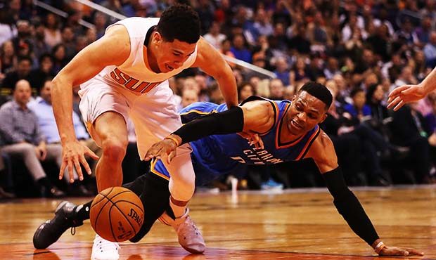 Devin Booker #1 of the Phoenix Suns and Russell Westbrook #0 of the Oklahoma City Thunder dive for ...