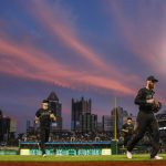 Pittsburgh Pirates third baseman Colin Moran, right, second baseman Adam Frazier, center, and shortstop Kevin Newman, left, come off the field as the setting sun lights up a colorful sky over the Pittsburgh skyline, in the fourth inning of the Pirates' baseball game against the Cincinnati Reds, Friday, Aug. 23, 2019. (AP Photo/Keith Srakocic)