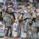 From left to right, Arizona Diamondbacks catcher Carson Kelly confers with starting pitcher Merrill Kelly as shortstop Nick Ahmed and first baseman Christian Walker look on after Kelly walked Colorado Rockies' Ian Desmond in the first inning of a baseball game Monday, Aug. 12, 2019, in Denver. (AP Photo/David Zalubowski)