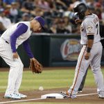 Arizona Diamondbacks third baseman Jake Lamb and San Francisco Giants' Donovan Solano watch the ball hit by Buster Posey bounce off the bag for a fair ball during the first inning of a baseball game Thursday, Aug. 15, 2019, in Phoenix. (AP Photo/Darryl Webb)