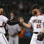 Arizona Diamondbacks catcher Carson Kelly and pitcher Archie Bradley (25) celebrate after the team defeated the Colorado Rockies 5-3 in a baseball game, Monday, Aug. 19, 2019, in Phoenix. (AP Photo/Rick Scuteri)