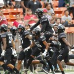 The Hawaii bench celebrates after Hawaii defensive back Kai Kaneshiro (24) intercepted an Arizona pass during the first quarter of an NCAA college football game Saturday, Aug. 24, 2019, in Honolulu. (AP Photo/Marco Garcia)