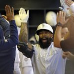Milwaukee Brewers' Eric Thames is congratulated in the dugout after hitting a solo home run during the fourth inning of a baseball game against the Arizona Diamondbacks, Saturday, Aug. 24, 2019, in Milwaukee. (AP Photo/Aaron Gash)