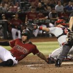 Arizona Diamondbacks' Ketel Marte scores ahead of the tag from Philadelphia Phillies catcher J.T. Realmuto, middle, as umpire Adam Hamari watches during the third inning of a baseball game Wednesday, Aug. 7, 2019, in Phoenix. (AP Photo/Ross D. Franklin)