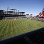 A lone worker moves up the first-base line as preparations begin at Coors Field before a baseball game between the Arizona Diamondbacks and Colorado Rockies Wednesday, Aug. 14, 2019, in Denver. (AP Photo/David Zalubowski)